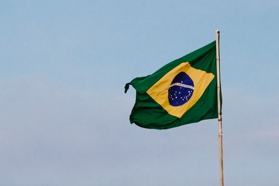 A Brazilian flag gracefully waving against a clear blue sky, symbolizing national pride and patriotism.
