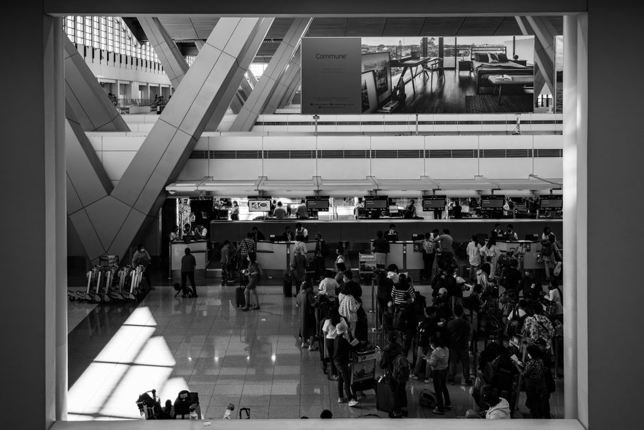 Black and white image of travelers at a bustling airport in Pasay, capturing the essence of global travel.
