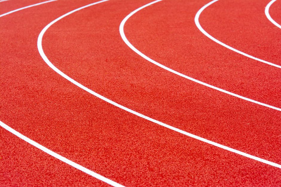 Curved sections of a red athletics track with white lane lines, perfect for sports imagery.