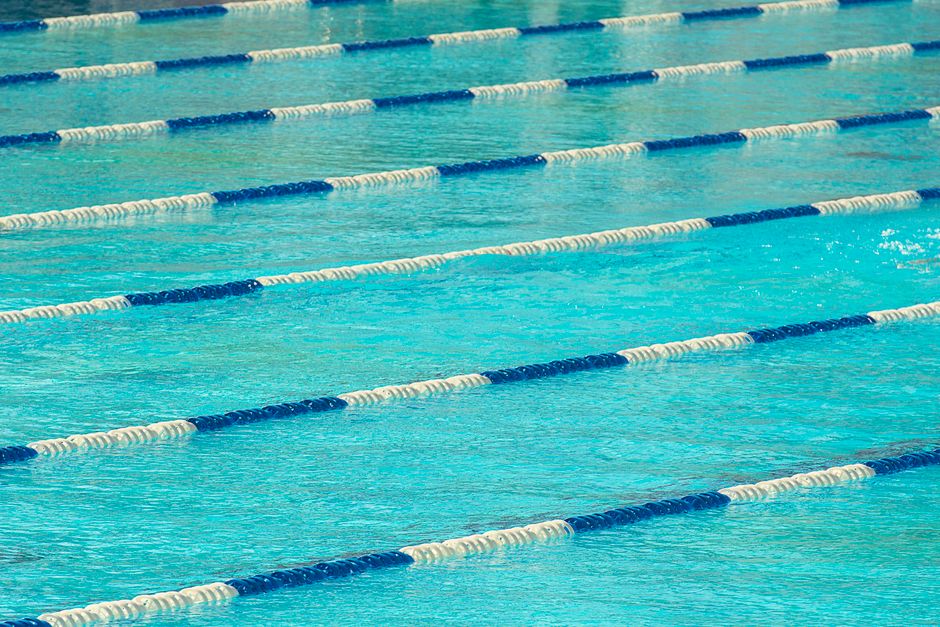 View of an Olympic swimming pool featuring floating lane dividers in calm water.