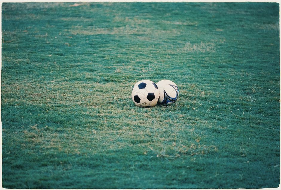 Two soccer balls resting on a lush green field, perfect for sports themes.