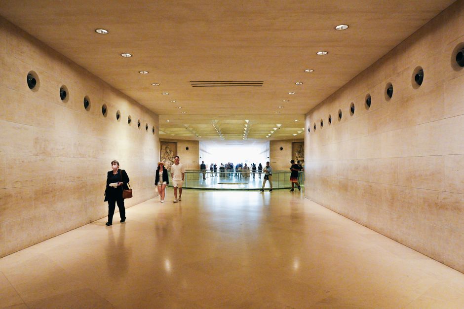 A well-lit museum corridor with visitors, featuring modern architecture.
