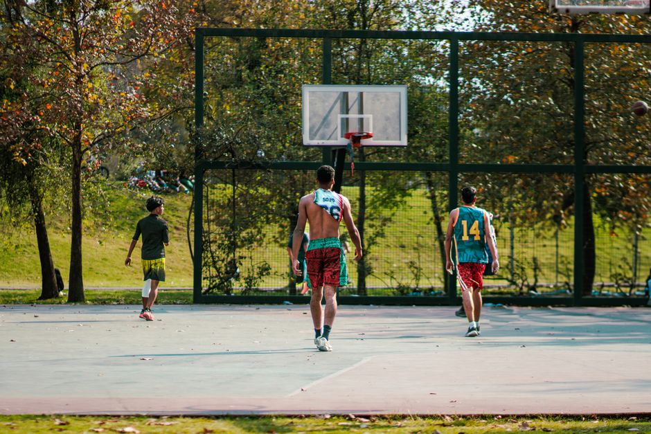 Energetic group of teenagers playing basketball outdoors on a sunny day.