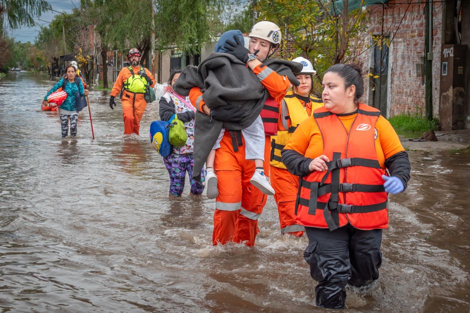 Rescue workers in orange gear helping people during a flood, showcasing bravery and teamwork.