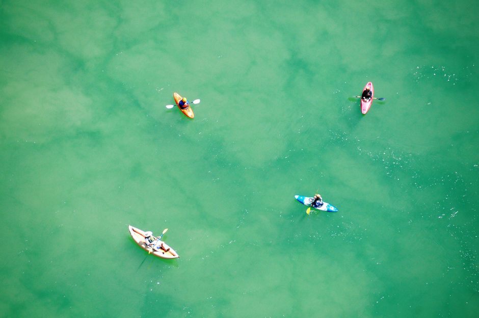 Aerial view of four kayakers enjoying a sunny day on turquoise waters, perfect for travel and leisure.