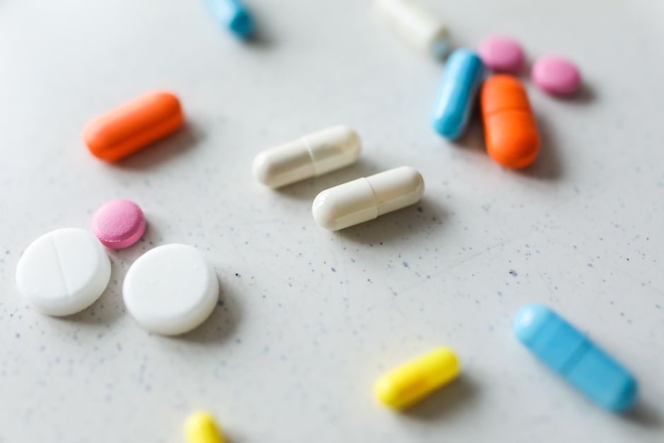 Close-up view of assorted colorful pills and tablets scattered on a white surface.
