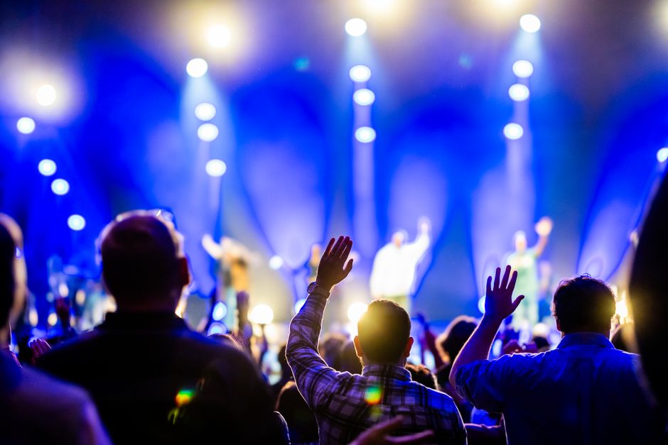 A vibrant concert scene with an enthusiastic audience enjoying live music under bright stage lights.