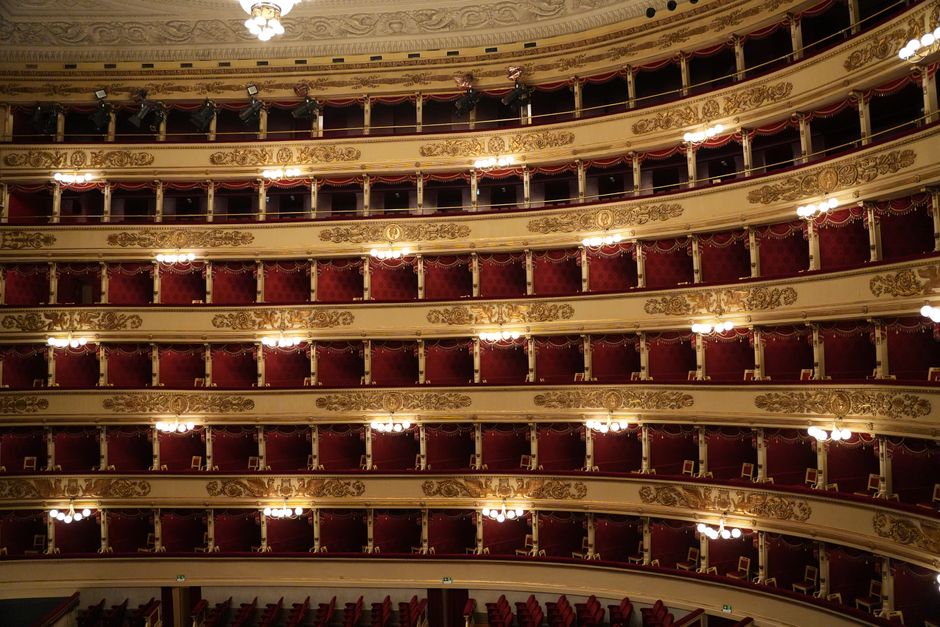 Ornate theater boxes at Teatro alla Scala, Milan, showcasing luxurious red velvet seats.