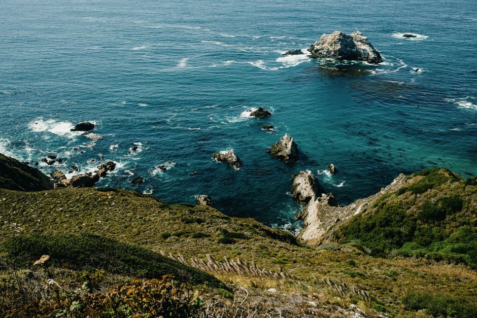Vista deslumbrante do litoral da Califórnia, com falésias rochosas e águas cristalinas do oceano azul.