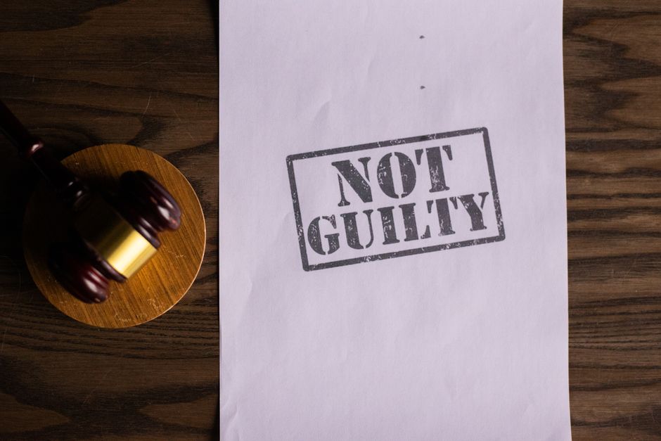 A courtroom document labeled 'Not Guilty' beside a gavel symbolizes justice.
