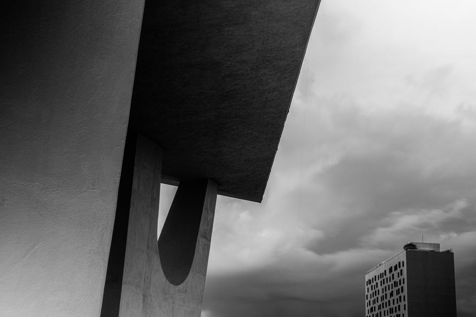 Black and white view of Brasília's modern architecture under a cloudy sky.