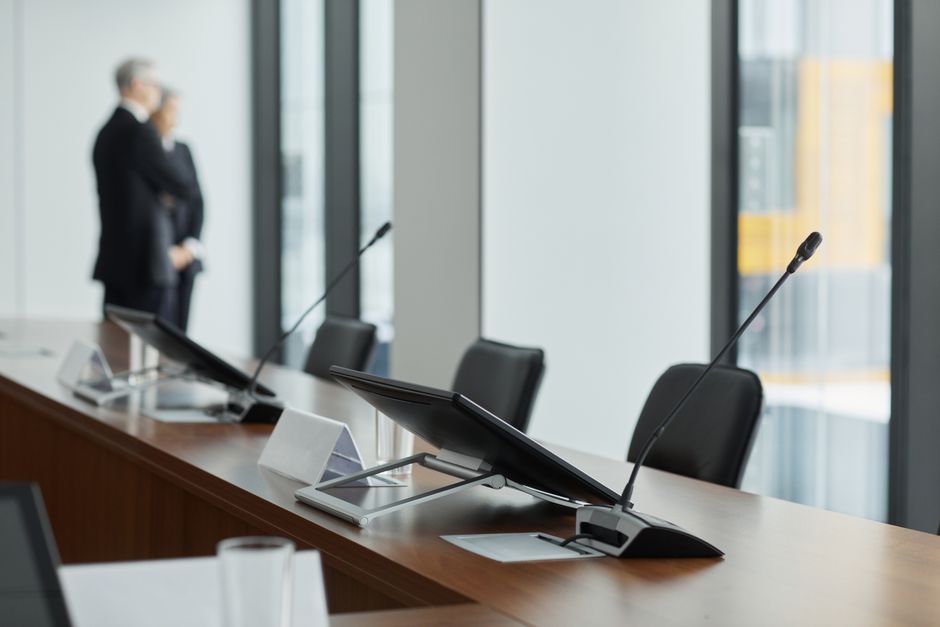 Sleek conference room setup with microphones, digital displays, and modern design elements.