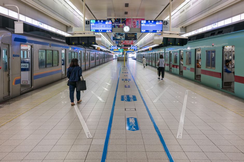 View of commuters walking in a clean, modern subway station with parked trains.