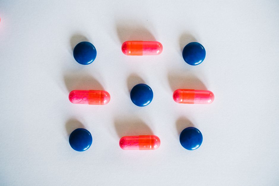 Various blue and pink pills and capsules arranged on a white background, showcasing medication.