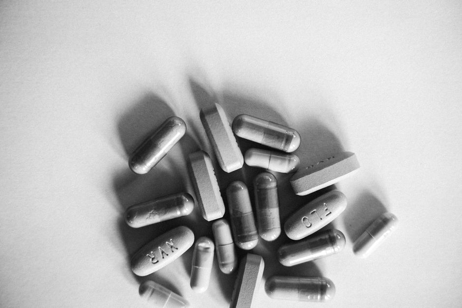 Grayscale image showing various capsules and tablets on a white surface.