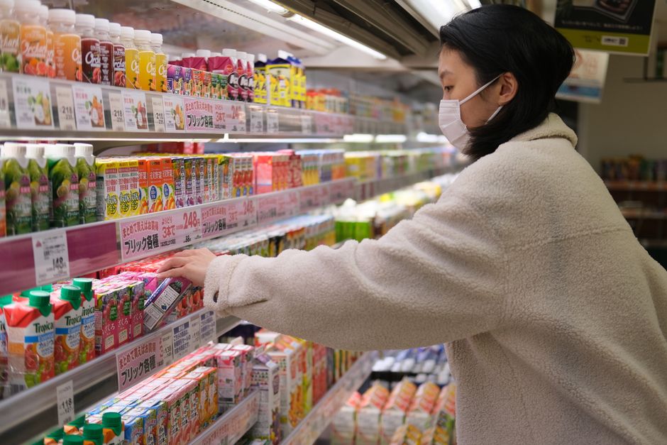 Masked woman shopping for beverages in a supermarket aisle