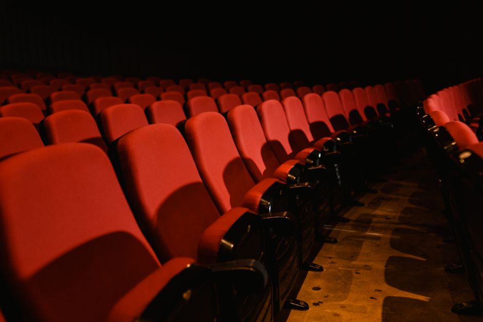 Rows of empty red seats in a dimly lit theater, perfect for cinema themes