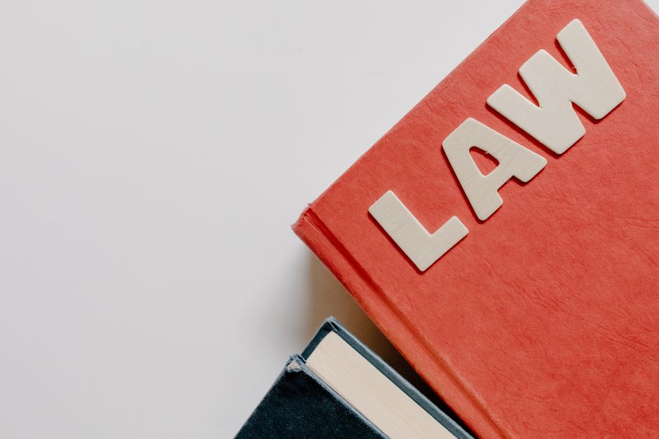 Red law textbook and dark book on white background, symbolizing education.